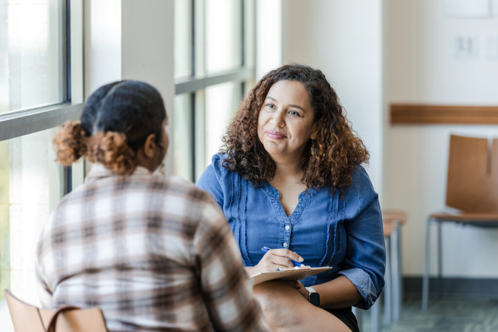 Patient talking to smiling therapist with clipboard and pen