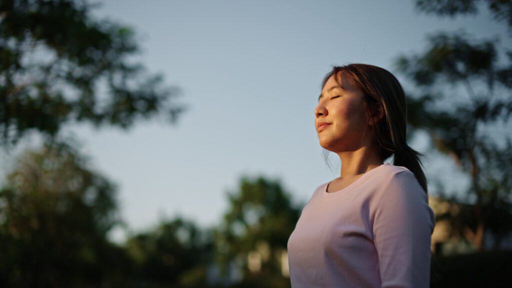 Person taking deep breath outside in sunshine